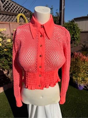 Hot pink fishnet-style cropped sweater jacket.